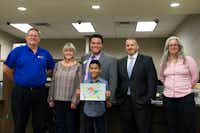 Ginnings Elementary fourth-grader Luis Hernandez shows off his prize-winning artwork with Denton ISD teachers and administrators at the Young Artists Night at UMB Bank. Hernandez won first place for his grade level in the annual Adopt-A-School Art Contest and received a Michael's gift card.Denton ISD