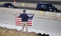 David Morgan of Highlands Ranch, Colo., holds an American flag as a procession of law enforcement vehicles accompany a hearse carrying the body of a sheriff's deputy shot and killed while responding to a domestic disturbance Sunday in Highlands Ranch, Colo.AP