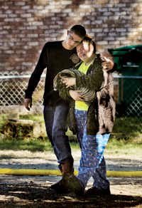 Erica Hilliard is comforted by William Urbany on Monday morning as she carries a pet rescued from a fire that destroyed her family’s home on Lakeview Drive in Lake Dallas.Al Key