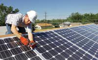 Brandon Karakashevich, an employee of Glean Power, a Denton solar and wind power company, installs solar panels on a Habitat for Humanity house on Lakey Street on May 13.Al Key - DRC