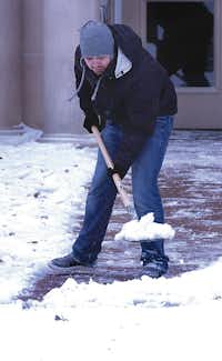 T.J. Zambrano shovels snow off the sidewalk in front of Clark Hall at the University of North Texas after Tuesday’s winter storm.